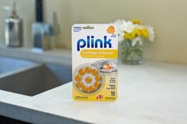 Plink® Garbage Disposal Freshener & Cleaner – Citrus Orange Scent package beside kitchen sink